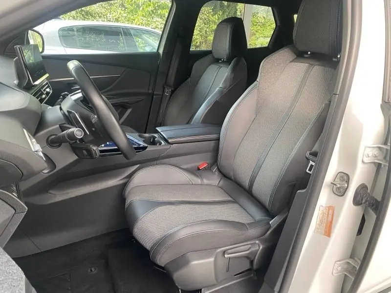 Vue intérieure côté conducteur du Peugeot 3008 blanc nacré, sièges en tissu et TEP Colyn Mistral gris avec inserts carbone.