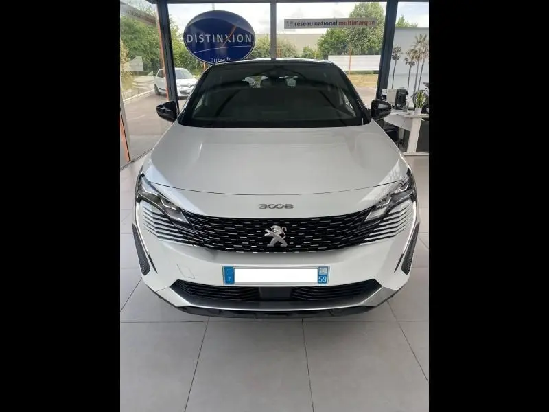 Vue de face d'un Peugeot 3008 blanc nacré avec calandre noire et logo lion chromé, en showroom.