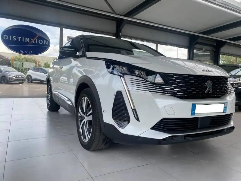 Peugeot 3008 blanc nacré vue 3/4 avant en intérieur, avec calandre noire et phares LED distinctifs.