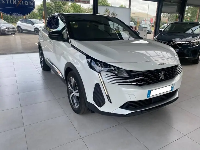 Peugeot 3008 blanc nacré vue 3/4 avant en showroom, avec calandre noire et phares LED distinctifs.