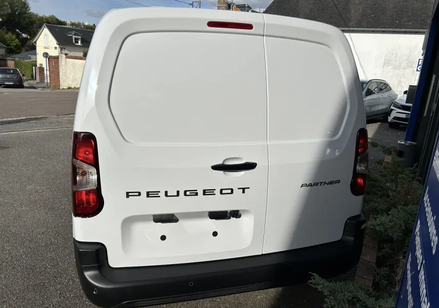Vue arrière d'un utilitaire blanc Peugeot Partner Fourgon avec portes battantes et feux rouges verticaux.