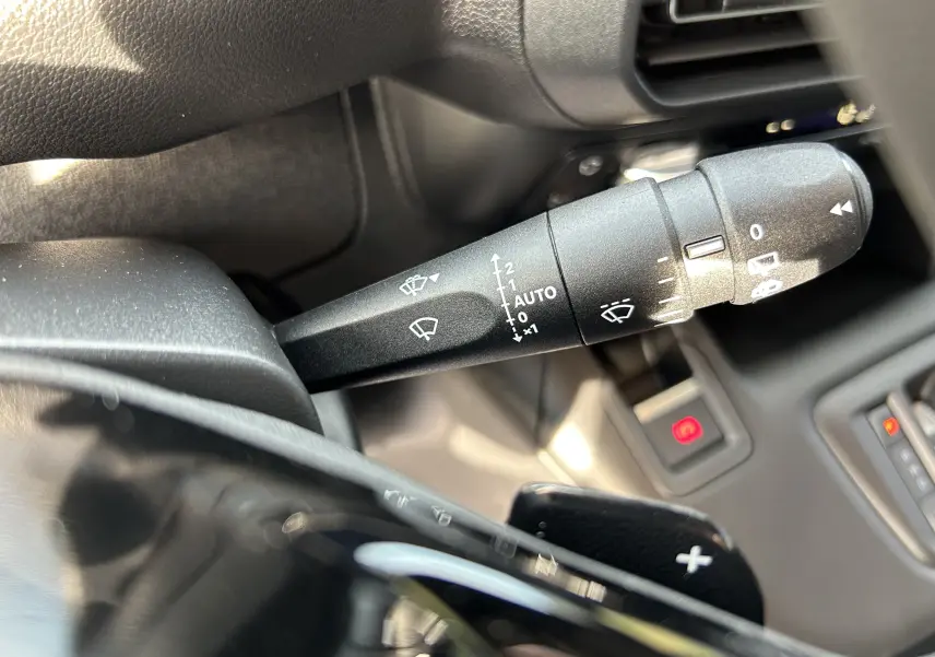 Gros plan sur la commande d'essuie-glace du Peugeot Partner Fourgon 2025, intérieur noir avec palettes au volant.