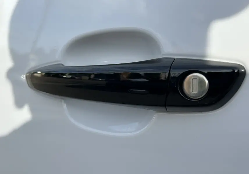 Poignée de porte noire sur porte blanche du Peugeot Partner Fourgon, vue rapprochée en extérieur.