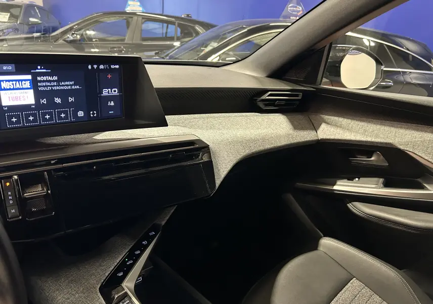 Vue intérieure côté passager du Peugeot 5008 gris Artense, mettant en valeur la planche de bord moderne et l'écran tactile central.