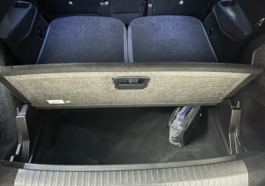 Vue plongeante sur le coffre ouvert du Peugeot 5008 gris Artense, montrant le compartiment de rangement sous plancher.