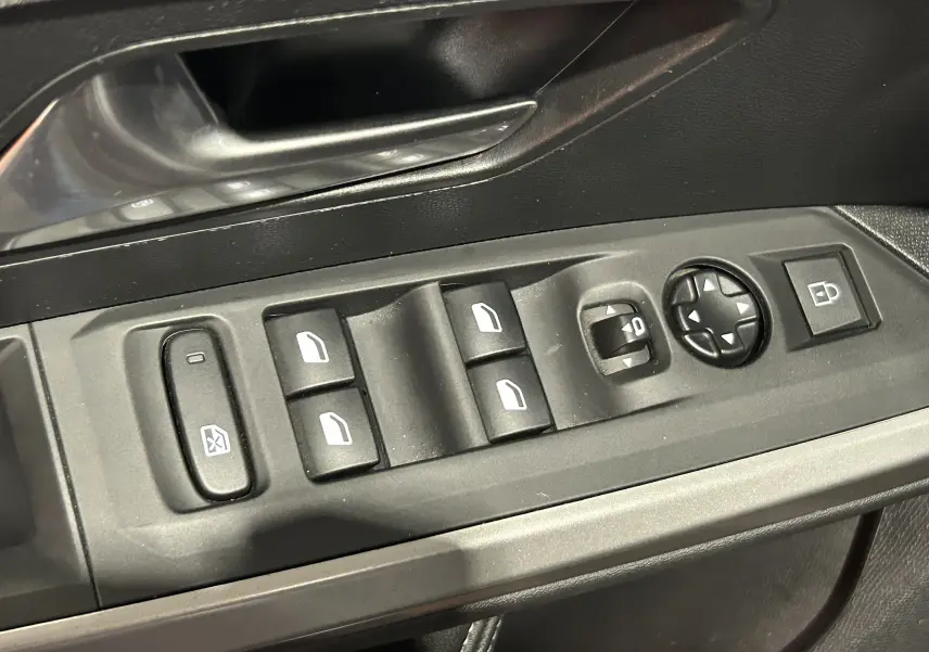 Gros plan sur les commandes de lève-vitres et rétroviseurs côté gauche intérieur du Peugeot 5008 gris Artense.