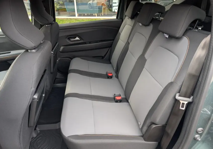 Vue latérale du siège arrière gris clair et noir du Dacia Jogger 2025 avec surpiqûres brun cuivré, porte ouverte côté droit.