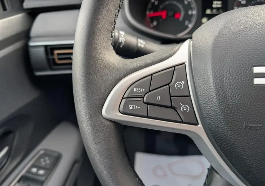 Gros plan sur les commandes de régulateur de vitesse au volant noir du Dacia Jogger 2025, intérieur gris acier.