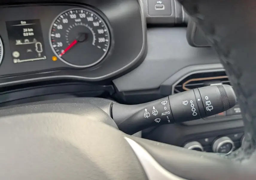 Gros plan sur la commande d'essuie-glace à droite du volant dans le tableau de bord gris du Dacia Jogger vert métallisé 2025.