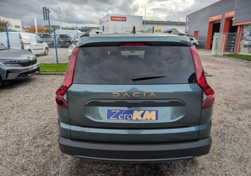 Vue arrière d'un Dacia Jogger 2025 vert métallisé avec logo brun cuivré et feux arrière verticaux distinctifs.