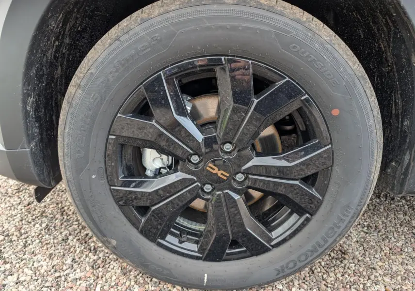 Gros plan sur la jante aluminium noire 16 pouces Mahalia du Dacia Jogger vert métallisé 2025, avec logo brun cuivré.