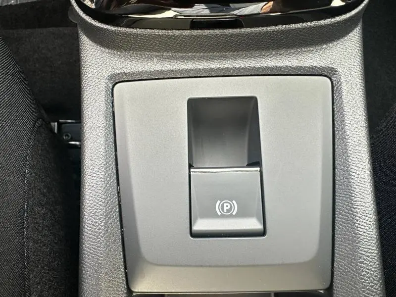 Gros plan sur le bouton de frein de stationnement électrique dans la console centrale du Citroën C3 Aircross gris Mercury.