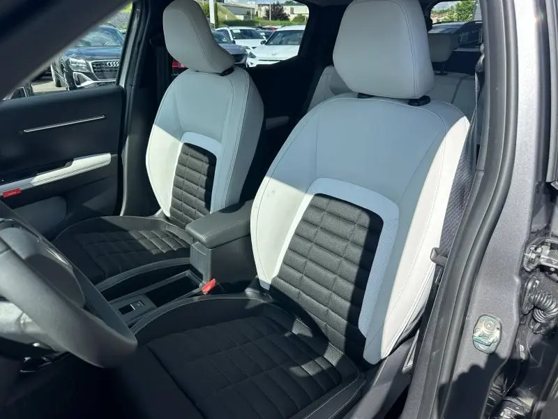 Vue intérieure côté avant droit du Citroën C3 Aircross gris Mercury, sièges bicolores noirs et blancs avec accoudoir central.