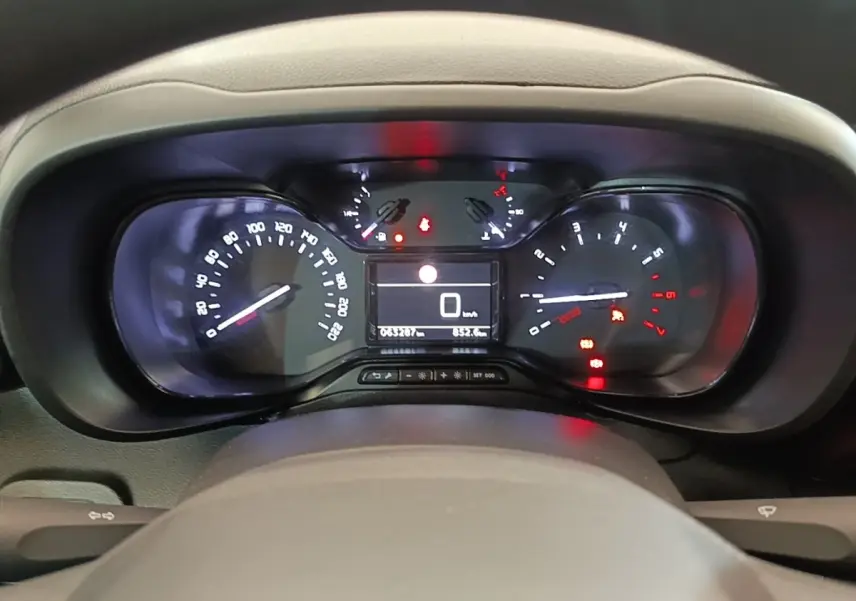 Vue rapprochée du tableau de bord digital du Citroën Berlingo blanc, affichant 0 km/h et divers voyants allumés.