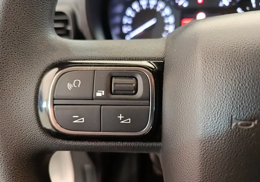 Gros plan sur les commandes du volant noir du Citroën Berlingo 2020, avec tableau de bord flou en arrière-plan.
