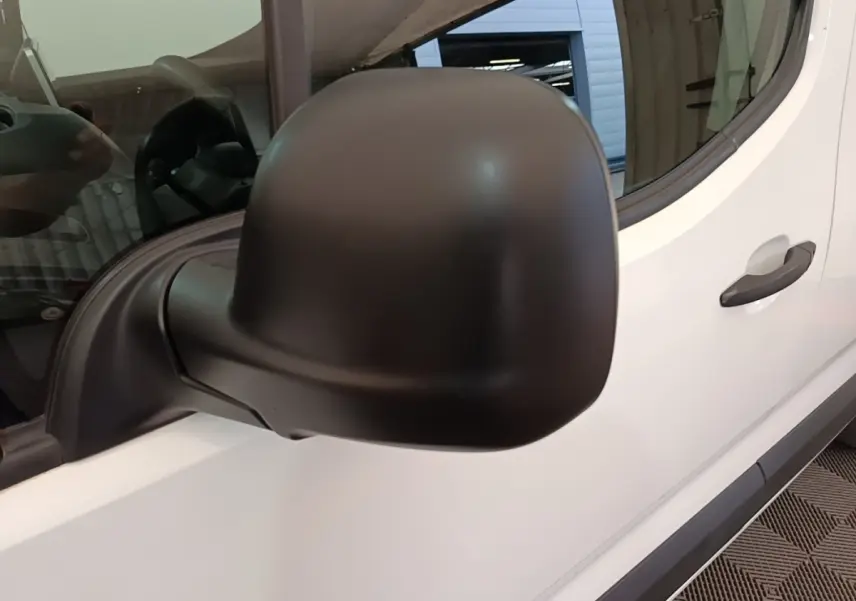 Gros plan sur le rétroviseur noir côté gauche du Citroën Berlingo blanc, avec porte et vitre visibles.