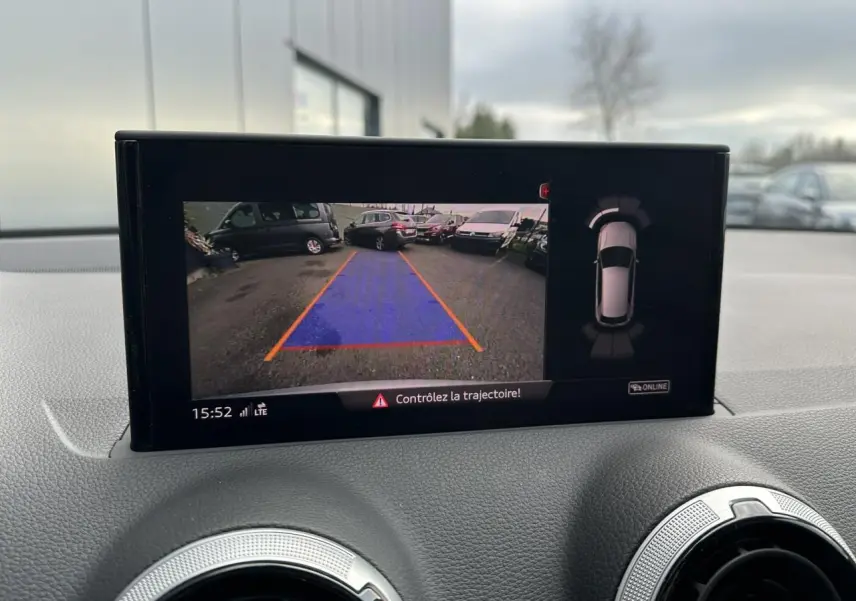 Écran intérieur montrant la caméra de recul avec guidage de trajectoire d’un Audi Q2 argent rosé, vue avant du tableau de bord.