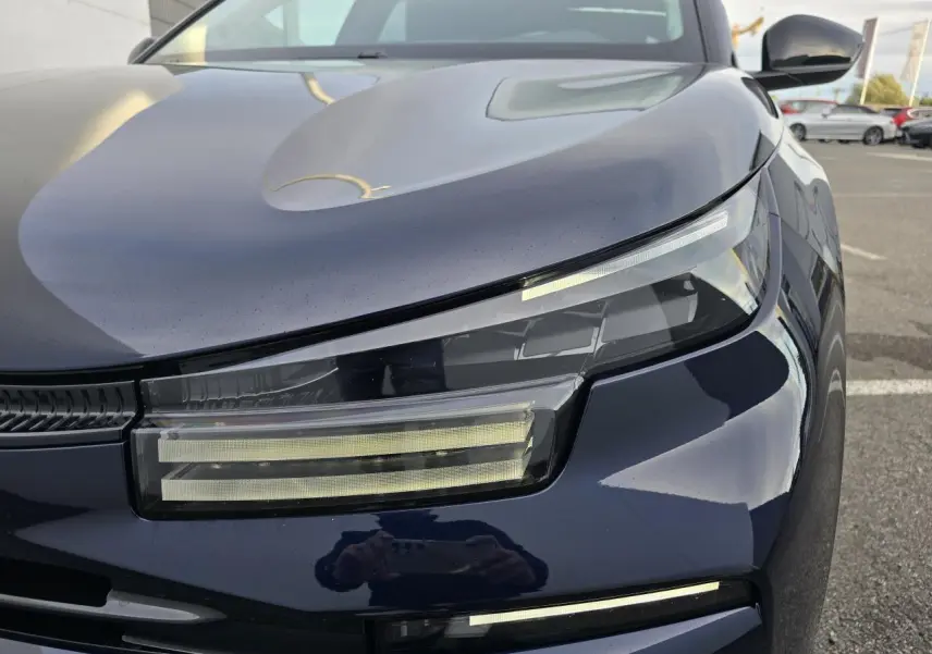 Gros plan sur le phare avant gauche de la Citroën C4 III bleu Éclipse avec toit noir, soulignant son design LED moderne.