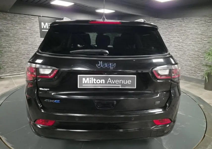 Vue arrière d'un Jeep Compass noir avec logo 4xe et toit noir dans un showroom intérieur.