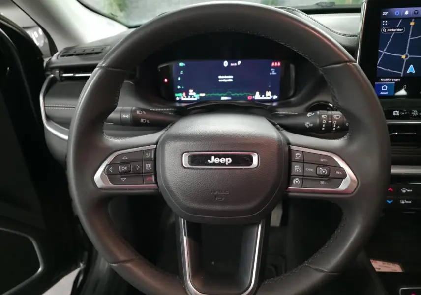 Vue rapprochée du volant cuir noir du Jeep Compass 2022 avec commandes intégrées et tableau de bord numérique.