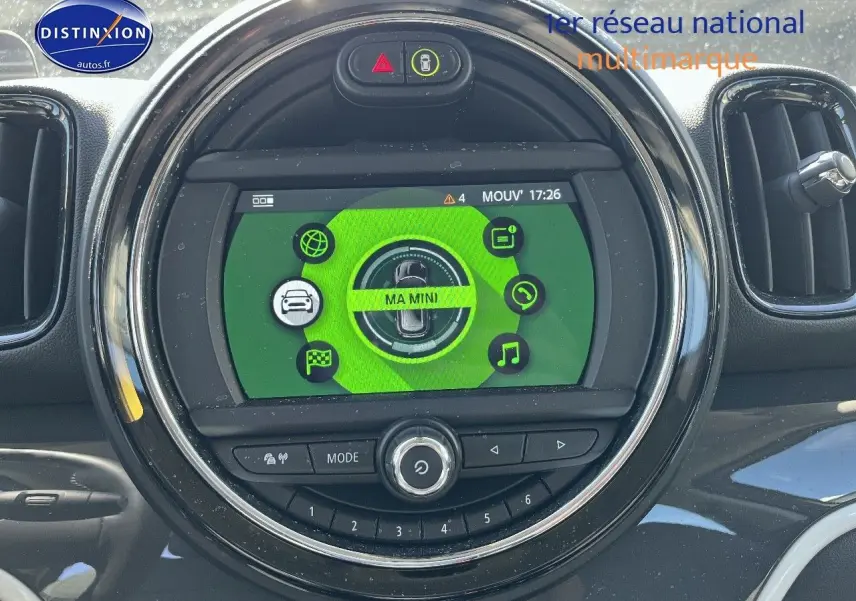 Vue rapprochée de l’écran central rond du tableau de bord d’une MINI Countryman avec interface verte et commandes intégrées.