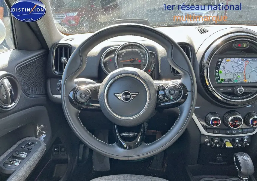 Vue intérieure centrée sur le volant cuir multifonction d'une MINI Countryman avec écran GPS et commandes au volant.