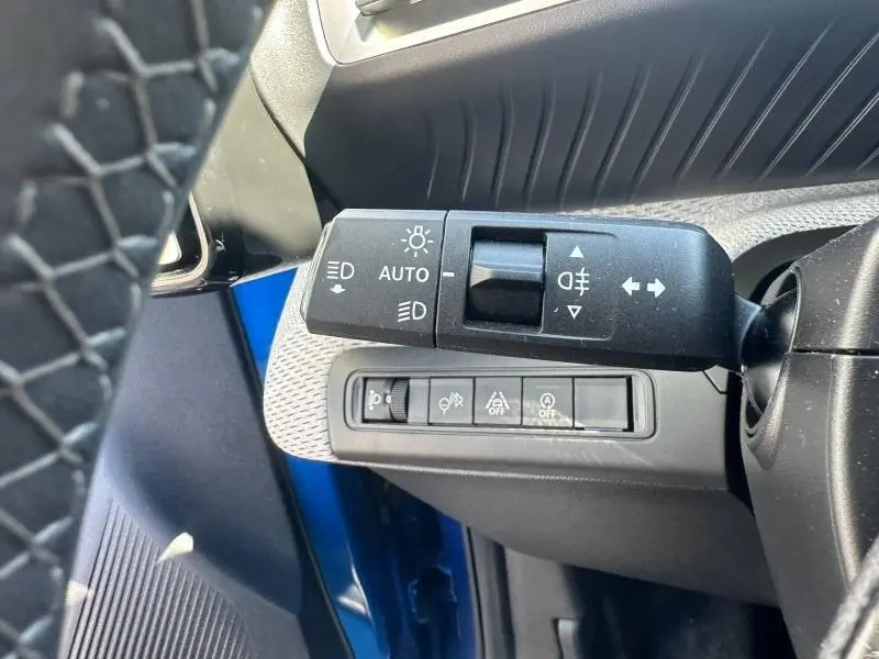 Gros plan sur la commande des feux et les boutons de fonctions sur la gauche du volant d'une Citroën C3 noire 2025.