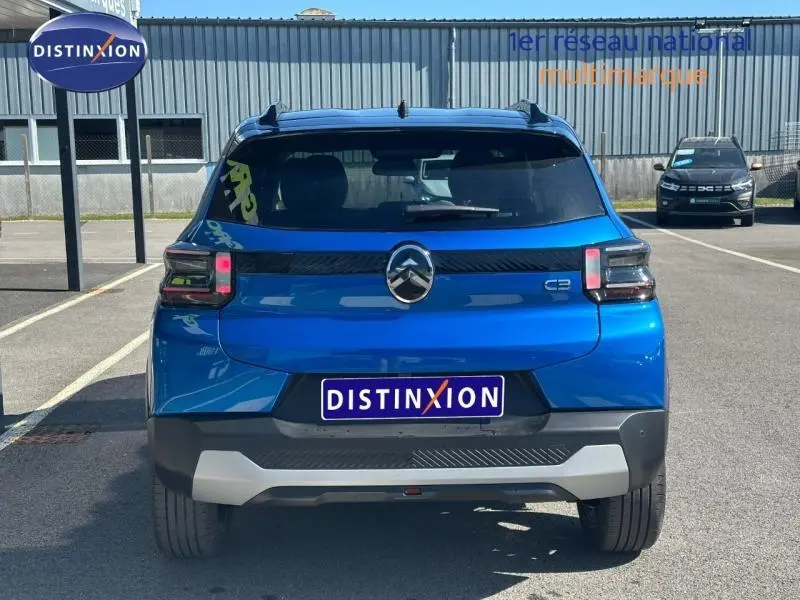 Vue arrière d'une Citroën C3 2025 bleue avec toit noir, feux arrière modernes et logo distinctif au centre.