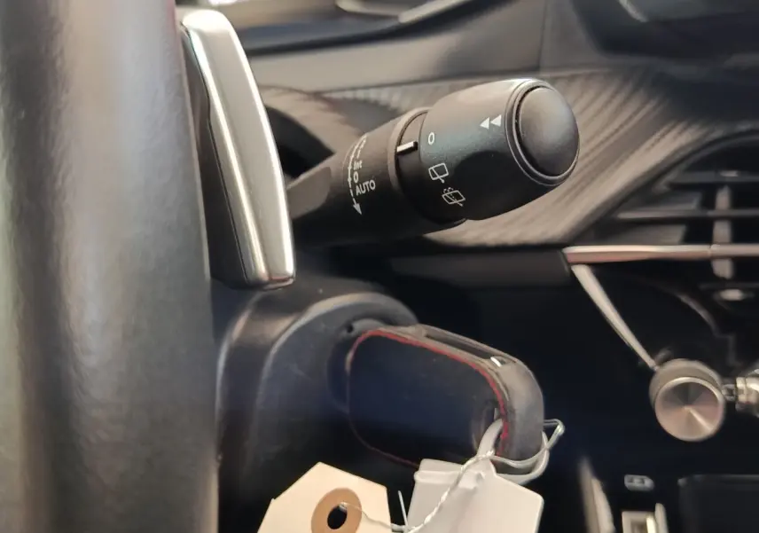 Gros plan sur la commande d’essuie-glace et le volant cuir du Peugeot 2008 blanc, intérieur avec détails carbone.