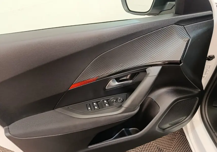 Vue intérieure de la porte avant gauche d’un Peugeot 2008 blanc, avec insert décoratif gris et bande rouge.