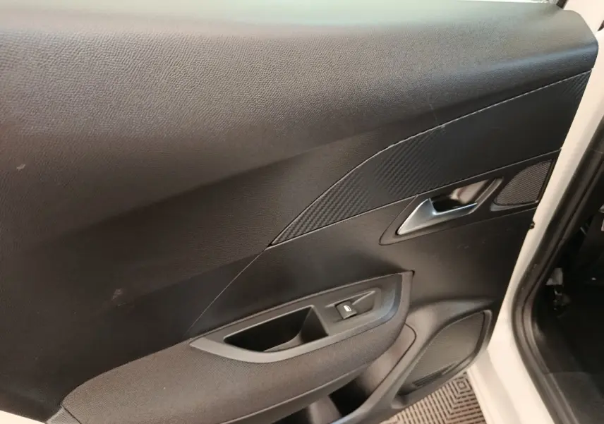 Vue intérieure de la porte avant droite noire du Peugeot 2008 blanc, avec poignée argentée et bouton de lève-vitre.