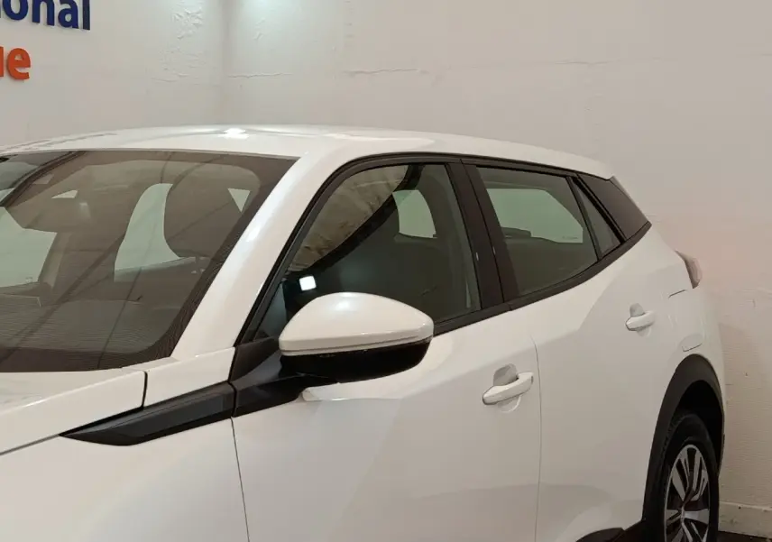 Vue de profil côté gauche d'un Peugeot 2008 blanc avec rétroviseur électrique et jantes alliage.