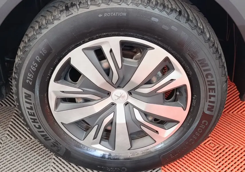Gros plan sur la roue avant droite d’un Peugeot 2008 blanc, avec jante alliage et pneu Michelin.
