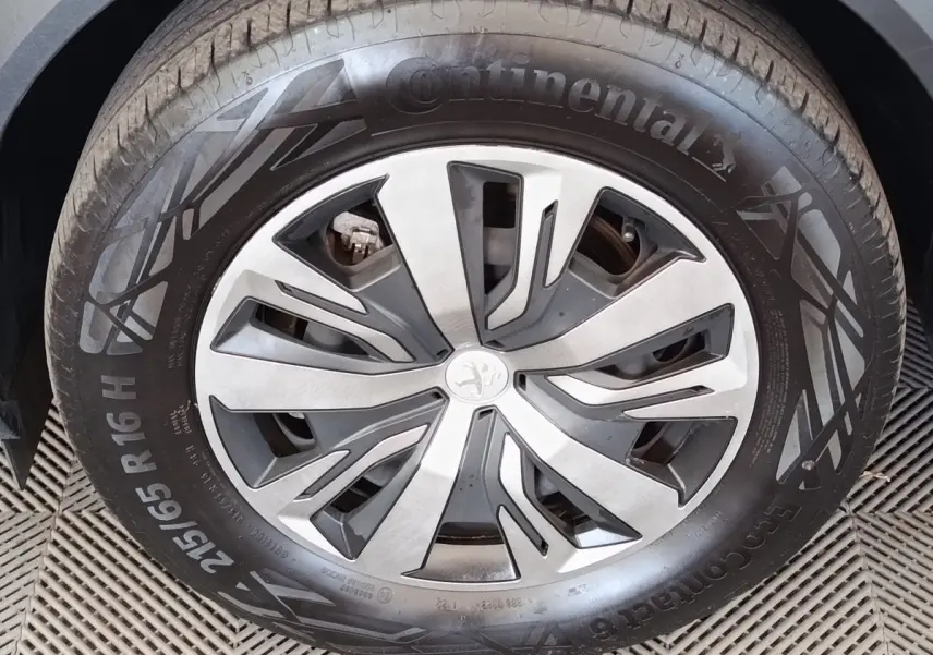 Gros plan sur la roue avant gauche d'un Peugeot 2008 blanc, jante alliage à design moderne et pneu Continental.