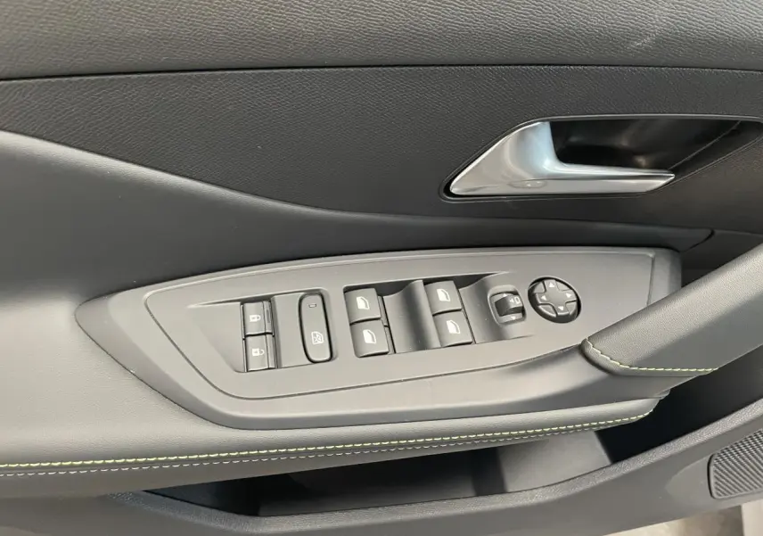 Détail de la porte avant gauche du Peugeot 308 gris Artense avec commandes des vitres et surpiqûres vert Adamite.
