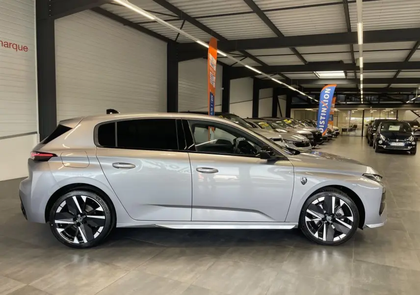 Peugeot 308 gris Artense vue de profil côté gauche en intérieur, jantes alliage bi-tons et vitres surteintées.