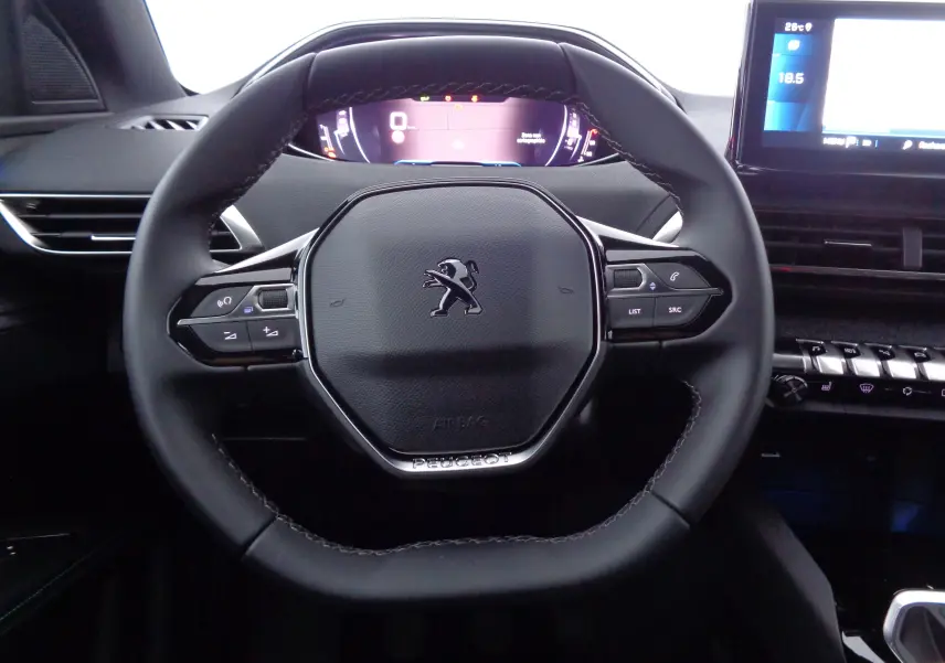 Volant noir en cuir avec logo Peugeot au centre, tableau de bord numérique et écran tactile à droite dans un Peugeot 5008 2023.
