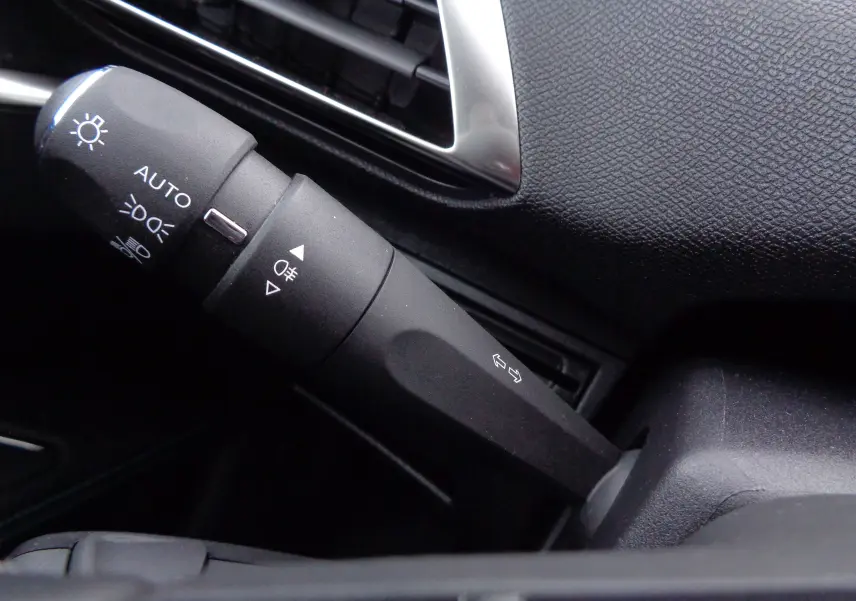 Gros plan sur la commande des phares et clignotants dans l'habitacle noir du Peugeot 5008 gris platinium 2023.