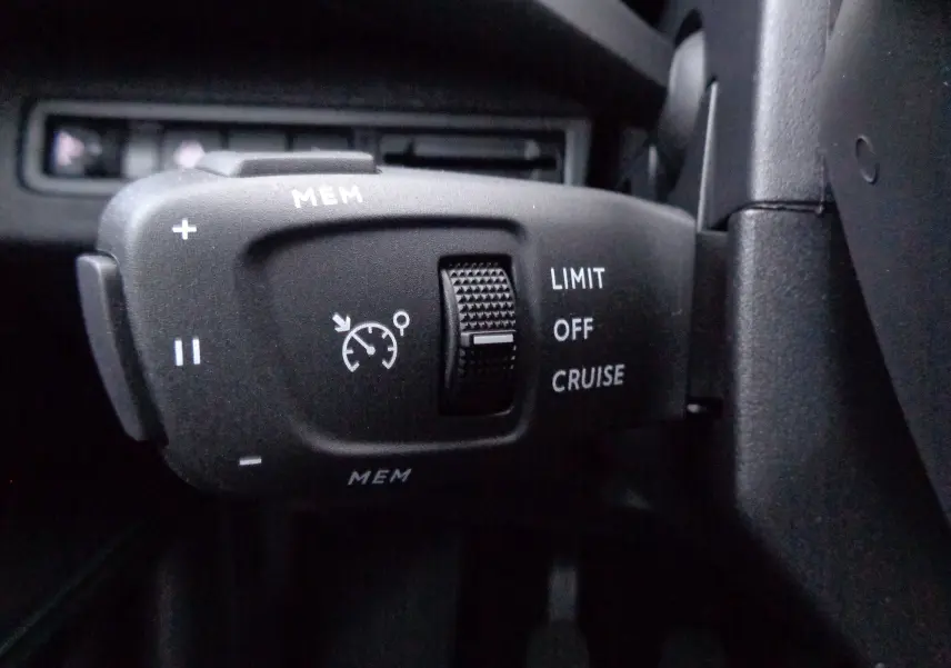 Gros plan sur la commande de régulateur de vitesse du Peugeot 5008 gris platinium 2023, côté gauche du volant.