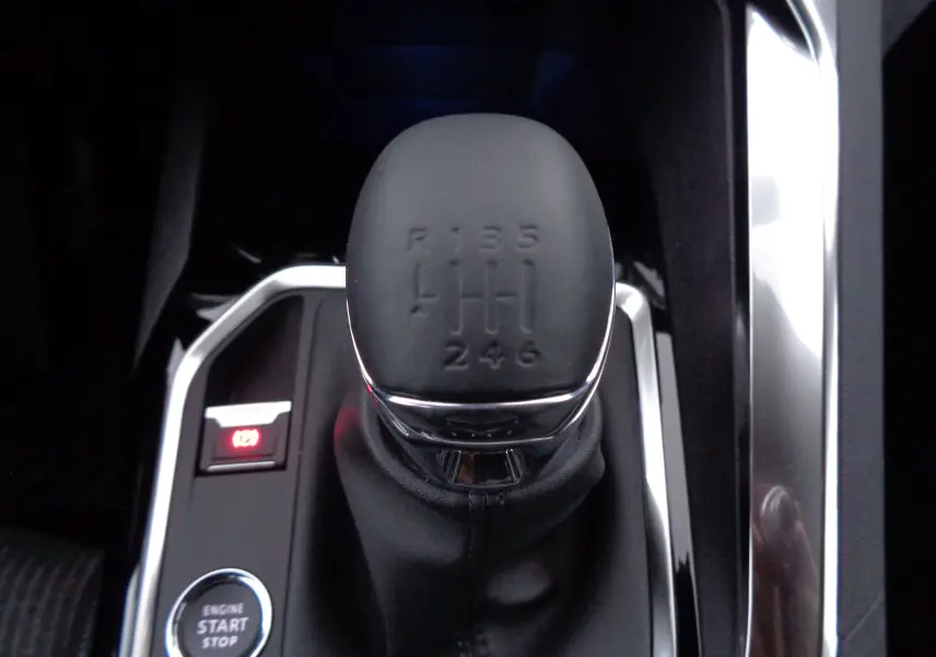 Gros plan sur le levier de vitesses manuel noir du Peugeot 5008 gris platinium, avec bouton start/stop à côté.
