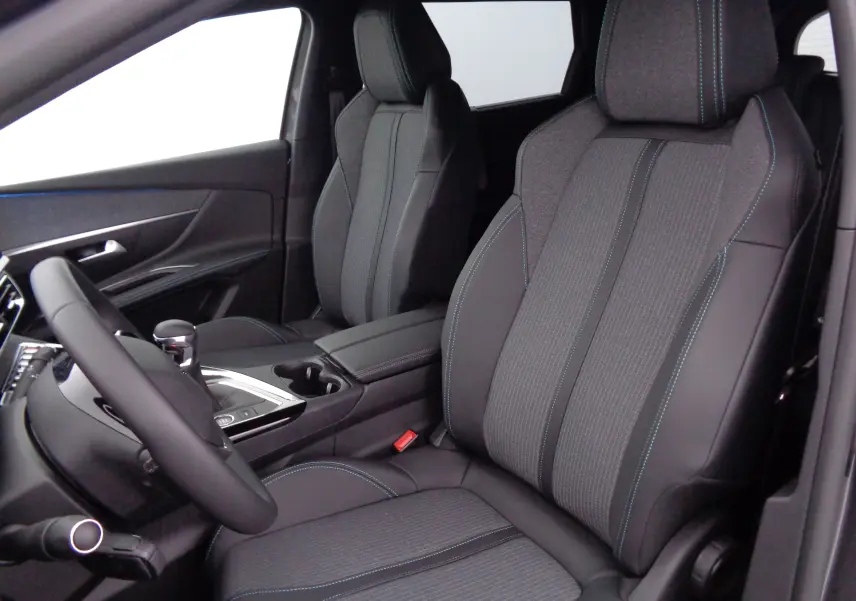 Intérieur avant du Peugeot 5008 2023, sièges gris anthracite avec surpiqûres bleues et console centrale moderne.