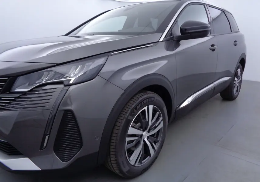 Vue 3/4 avant droit d'un Peugeot 5008 gris platinium métallisé avec jantes alliage et phares LED distinctifs.