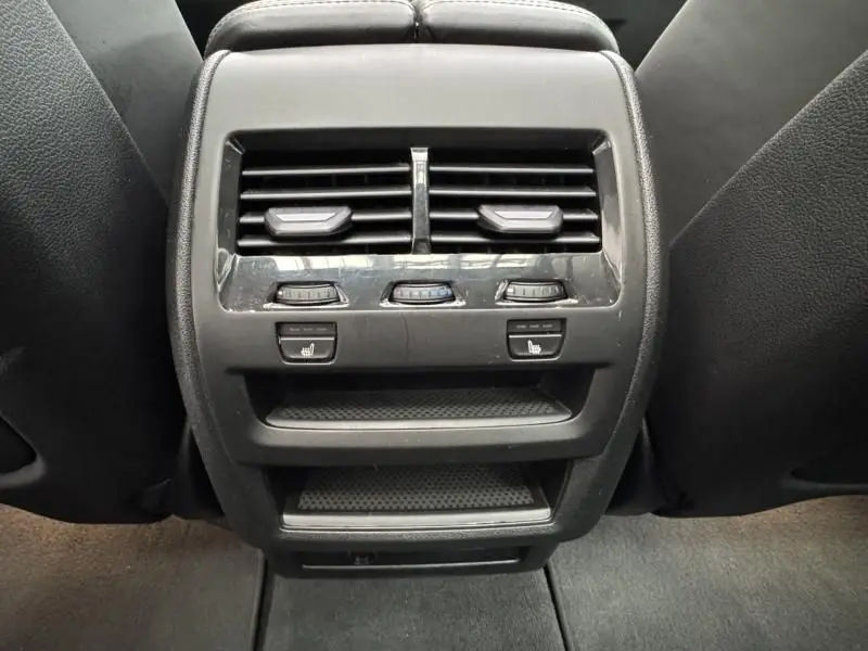 Vue rapprochée des commandes de climatisation arrière et sièges chauffants du BMW X5 xDrive50e noir 2023.