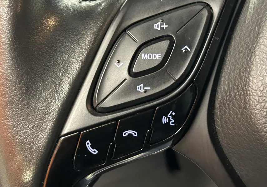 Gros plan sur les commandes au volant noir du Toyota C-HR Hybride 122h Edition 2WD 2021, boutons audio et téléphone.