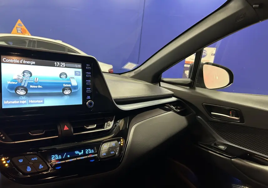 Intérieur du Toyota C-HR Hybride 2021 vu côté passager, avec écran tactile affichant le contrôle d'énergie et climatisation digitale.