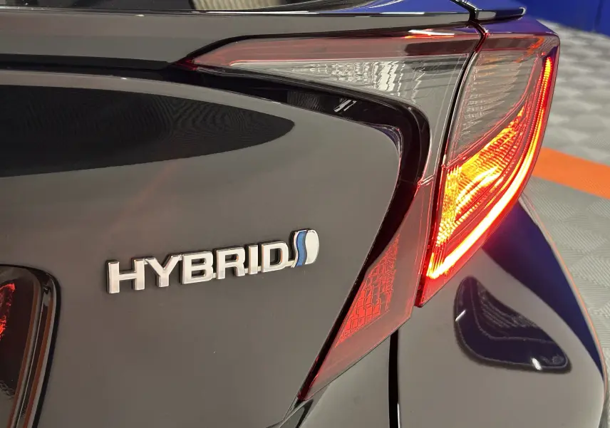 Gros plan sur le feu arrière droit et le logo HYBRID d'un Toyota C-HR hybride noir métal 2021.