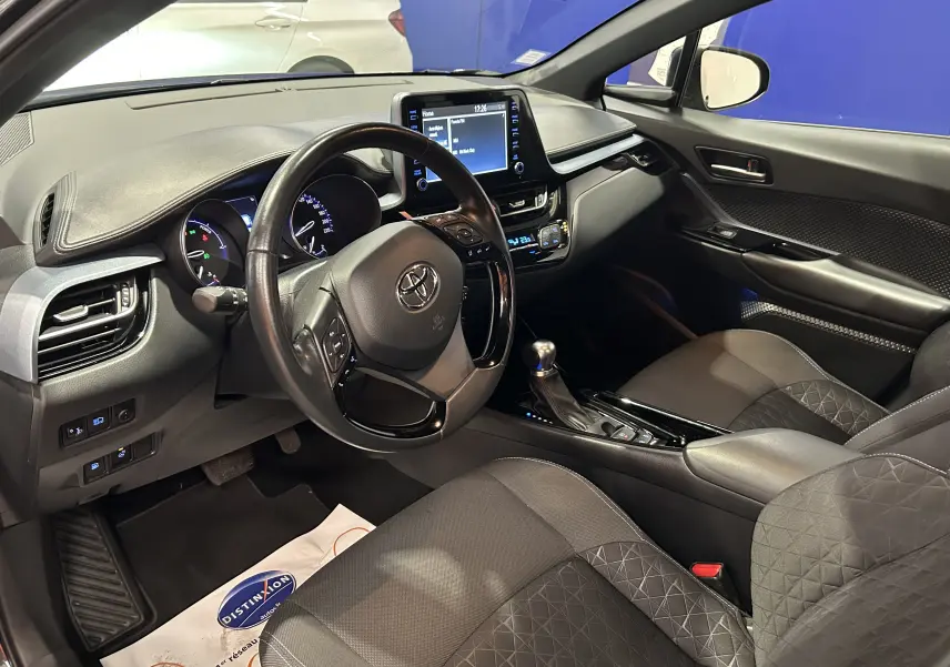 Intérieur avant du Toyota C-HR Hybride 122h noir métal, volant multifonction et écran tactile central visible.