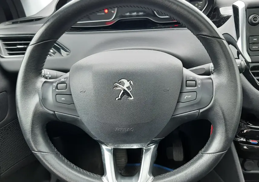 Volant en cuir noir de Peugeot 208 2019, avec commandes intégrées et tableau de bord en arrière-plan.