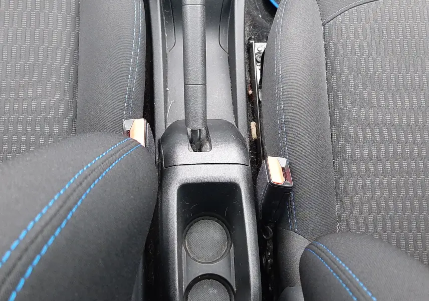 Vue plongeante sur la console centrale et les sièges avant noirs avec surpiqûres bleues d'une Peugeot 208 Bleu Nuit 2019.