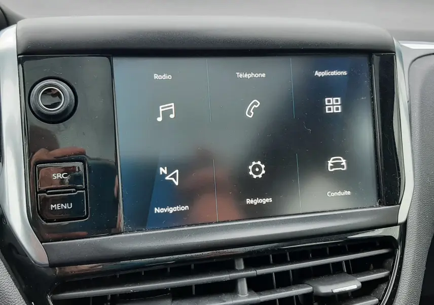 Écran tactile central du tableau de bord de la Peugeot 208 bleu nuit, affichant les menus radio, téléphone et navigation.